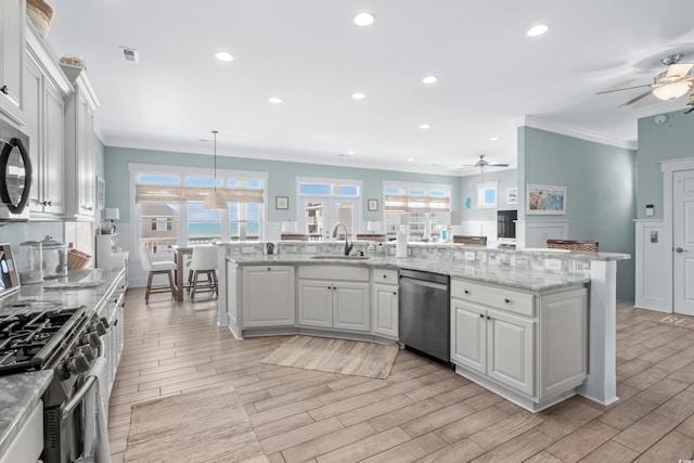 kitchen featuring sink, appliances with stainless steel finishes, white cabinetry, a kitchen island with sink, and decorative light fixtures