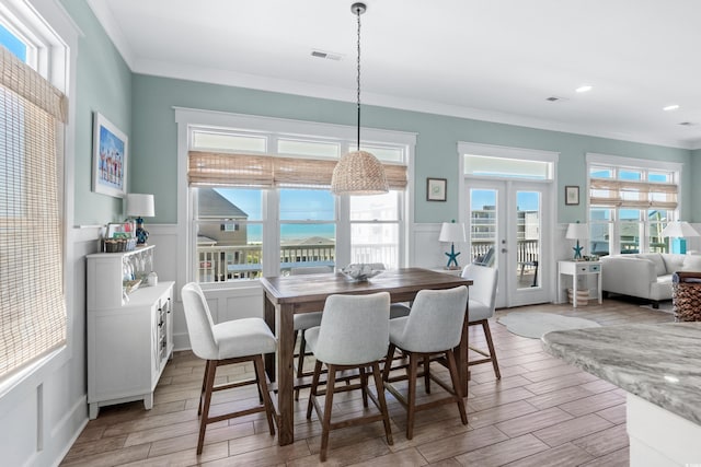 dining area featuring french doors, a water view, and crown molding