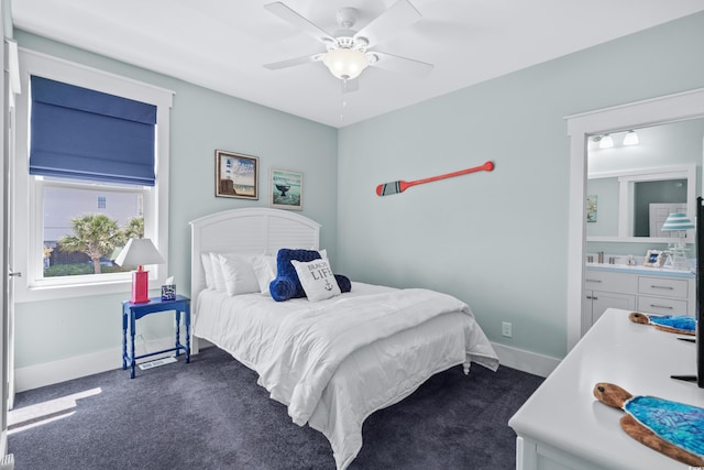 bedroom with ceiling fan, ensuite bathroom, and dark carpet