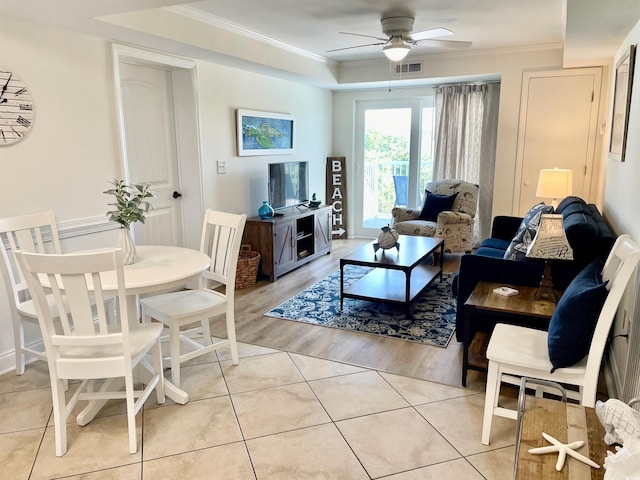 tiled living room with crown molding, ceiling fan, and a raised ceiling