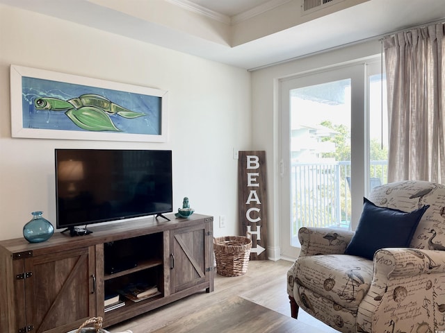 living room featuring light hardwood / wood-style flooring, crown molding, plenty of natural light, and a tray ceiling