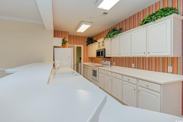 kitchen with white cabinetry, sink, white appliances, and kitchen peninsula