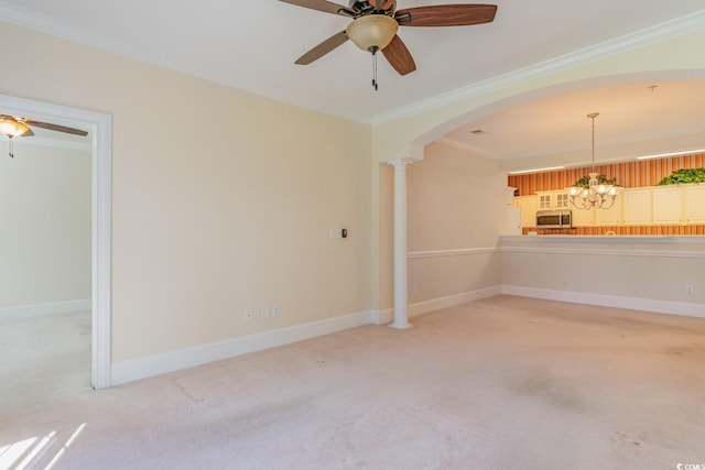 carpeted spare room with ceiling fan with notable chandelier, ornamental molding, and decorative columns