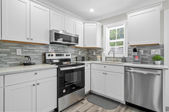 kitchen with white cabinets, light hardwood / wood-style flooring, stainless steel appliances, backsplash, and sink