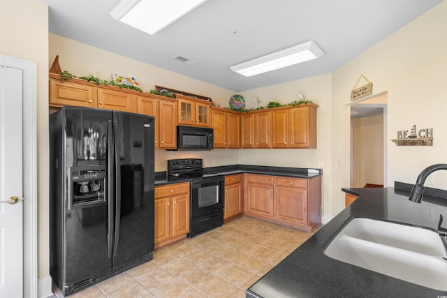 kitchen with black appliances, light tile patterned floors, and sink