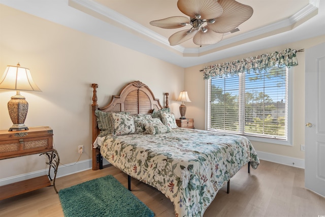 bedroom with a tray ceiling, ceiling fan, hardwood / wood-style floors, and ornamental molding