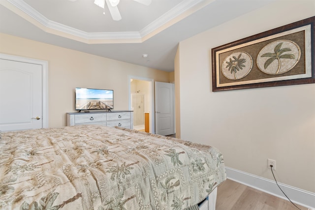 bedroom with a tray ceiling, ceiling fan, ornamental molding, and light hardwood / wood-style floors