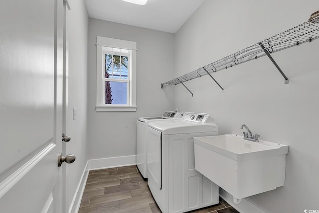 clothes washing area featuring hardwood / wood-style flooring, separate washer and dryer, and sink