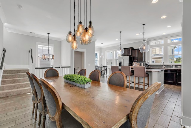 dining area featuring a notable chandelier, plenty of natural light, light hardwood / wood-style floors, and crown molding