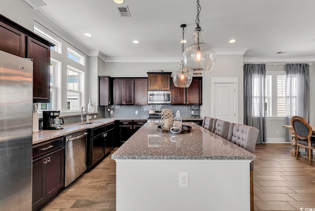 kitchen featuring appliances with stainless steel finishes, sink, plenty of natural light, and a center island