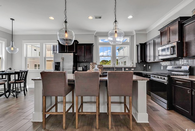 kitchen with stainless steel appliances, plenty of natural light, dark hardwood / wood-style flooring, and a kitchen island