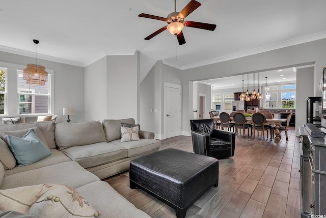 living room featuring ceiling fan with notable chandelier, wood-type flooring, and ornamental molding