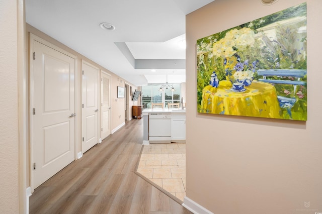 hall with light hardwood / wood-style floors and an inviting chandelier