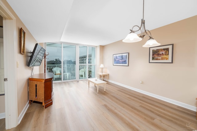 unfurnished room featuring an inviting chandelier, light hardwood / wood-style floors, and a wall of windows