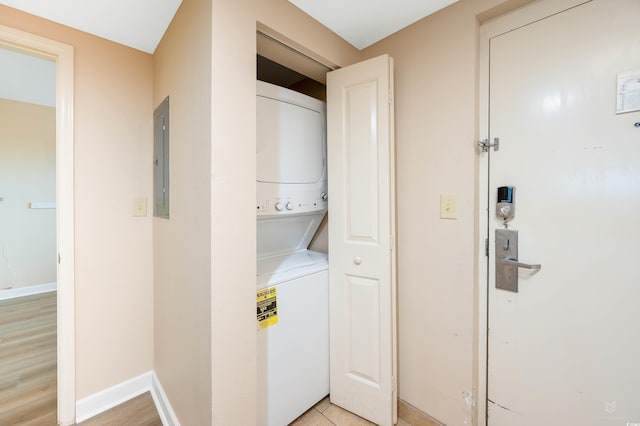 washroom featuring electric panel, light hardwood / wood-style flooring, and stacked washer / dryer