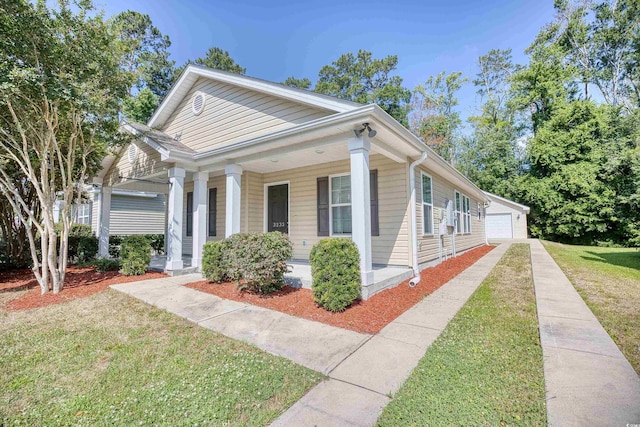 view of front of property featuring a porch, a garage, an outbuilding, and a front yard