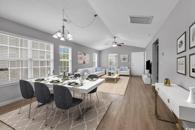 dining room featuring ceiling fan with notable chandelier, lofted ceiling, and hardwood / wood-style floors