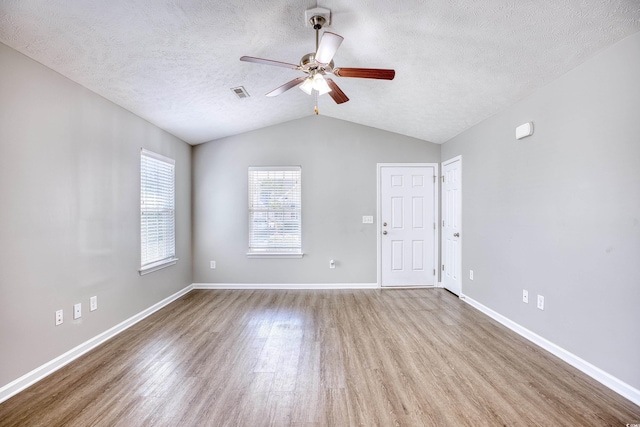 spare room with a textured ceiling, wood-type flooring, lofted ceiling, and ceiling fan