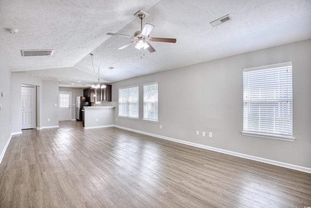 unfurnished living room featuring a textured ceiling, ceiling fan with notable chandelier, wood-type flooring, and vaulted ceiling