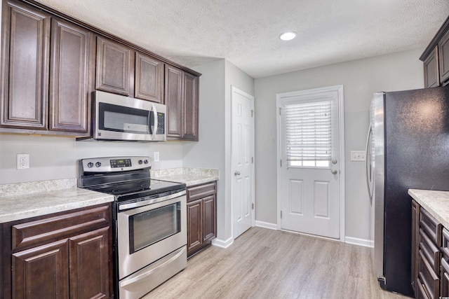 kitchen with dark brown cabinetry, appliances with stainless steel finishes, and light wood-type flooring