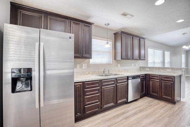 kitchen featuring stainless steel appliances, sink, pendant lighting, light hardwood / wood-style floors, and dark brown cabinetry