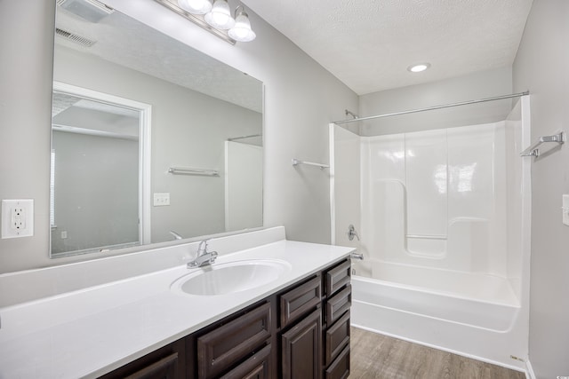 bathroom with vanity, shower / washtub combination, a textured ceiling, and hardwood / wood-style flooring