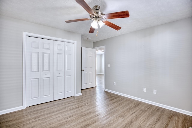 unfurnished bedroom featuring a textured ceiling, light hardwood / wood-style flooring, a closet, and ceiling fan