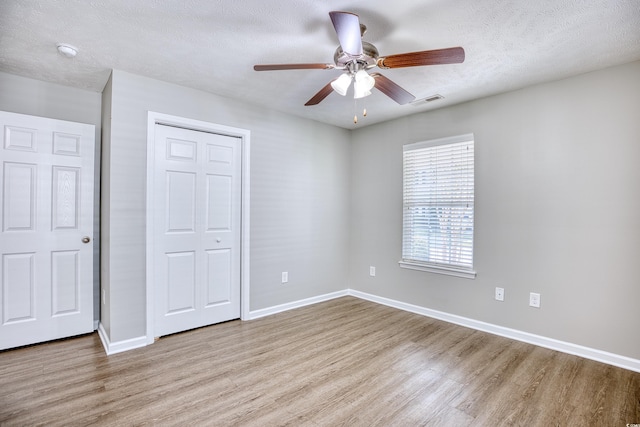 unfurnished bedroom with ceiling fan, a textured ceiling, hardwood / wood-style flooring, and a closet