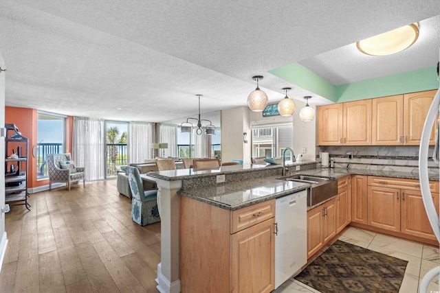 kitchen with sink, pendant lighting, white dishwasher, and kitchen peninsula