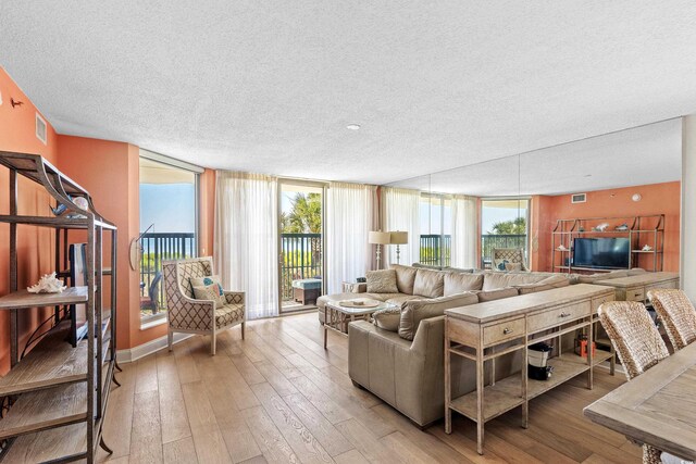 living room featuring plenty of natural light, light hardwood / wood-style floors, and a wall of windows