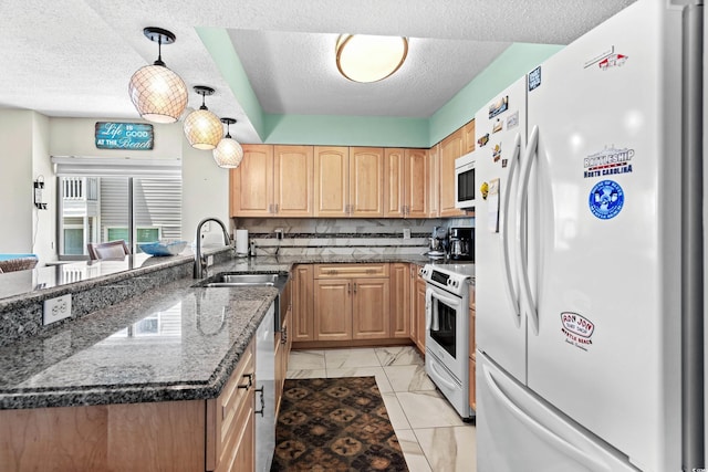 kitchen featuring sink, hanging light fixtures, dark stone countertops, white appliances, and backsplash