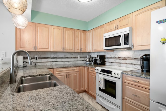 kitchen with range with electric cooktop, sink, light brown cabinetry, and refrigerator