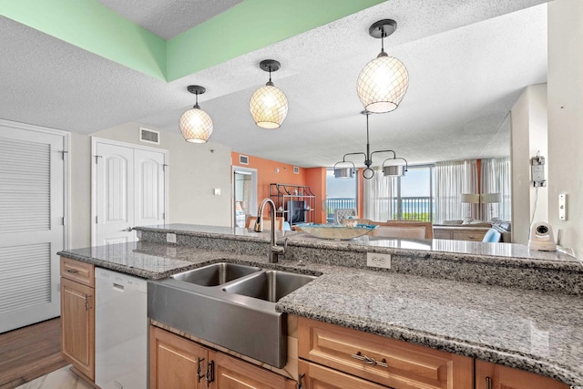 kitchen featuring stone counters, dishwasher, sink, and a textured ceiling