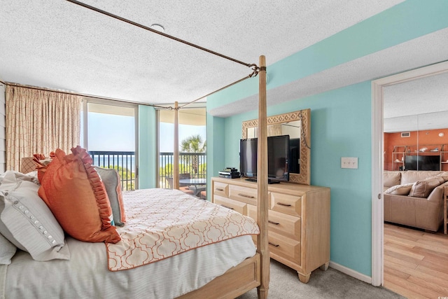 bedroom featuring access to exterior, a textured ceiling, and a wall of windows