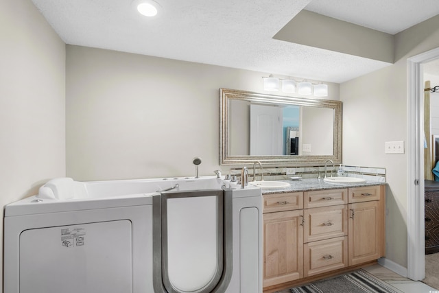 bathroom featuring tasteful backsplash, vanity, washer and dryer, and a textured ceiling