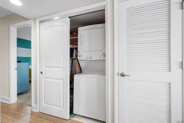 clothes washing area featuring stacked washer / dryer and light hardwood / wood-style flooring