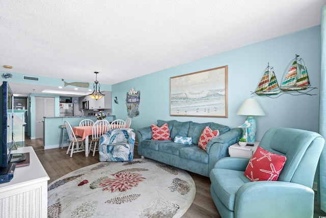 living area with a textured ceiling, wood finished floors, and visible vents