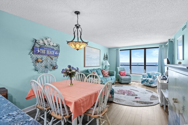 dining space with a textured ceiling and hardwood / wood-style floors