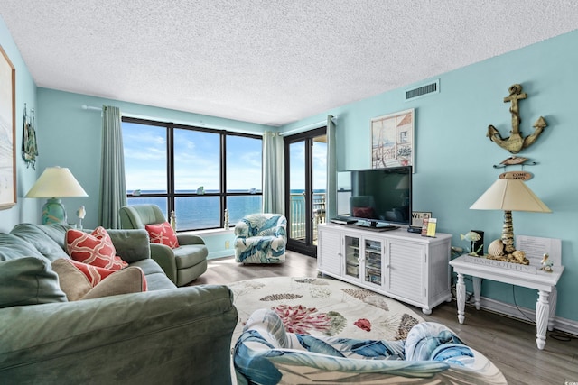 living area with visible vents, a textured ceiling, baseboards, and wood finished floors