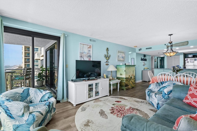 living area featuring a textured ceiling, visible vents, and wood finished floors