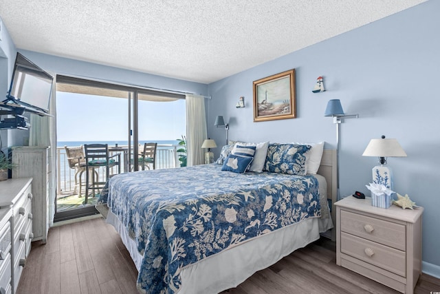 bedroom with access to outside, a textured ceiling, and wood finished floors