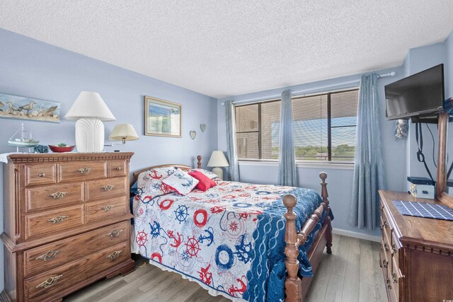 bedroom with light hardwood / wood-style floors and a textured ceiling