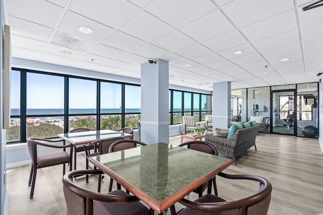 interior space with a water view, a drop ceiling, and light wood finished floors