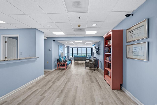 hallway featuring light wood-type flooring and a drop ceiling