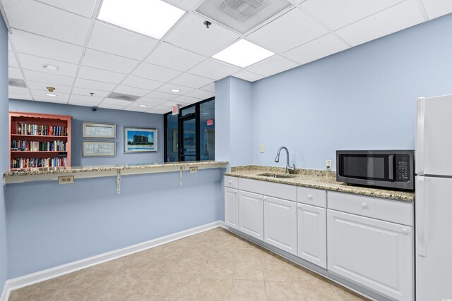 kitchen with sink, a paneled ceiling, white cabinets, and white refrigerator