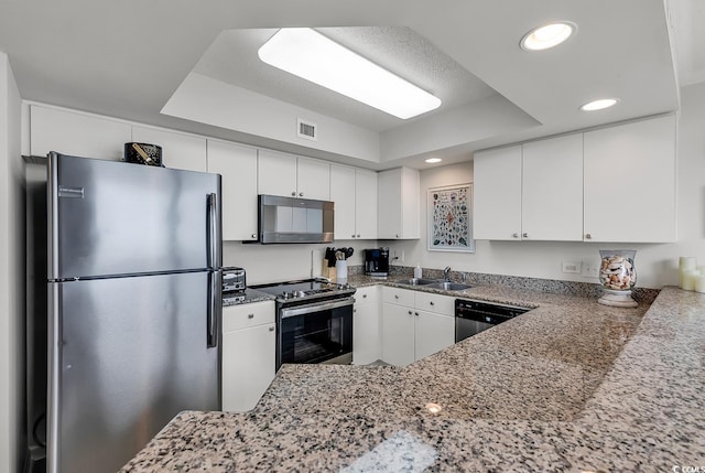 kitchen featuring dark stone counters, sink, white cabinetry, kitchen peninsula, and stainless steel appliances