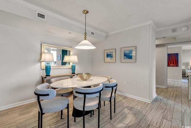 dining room with light hardwood / wood-style floors, a textured ceiling, and ornamental molding