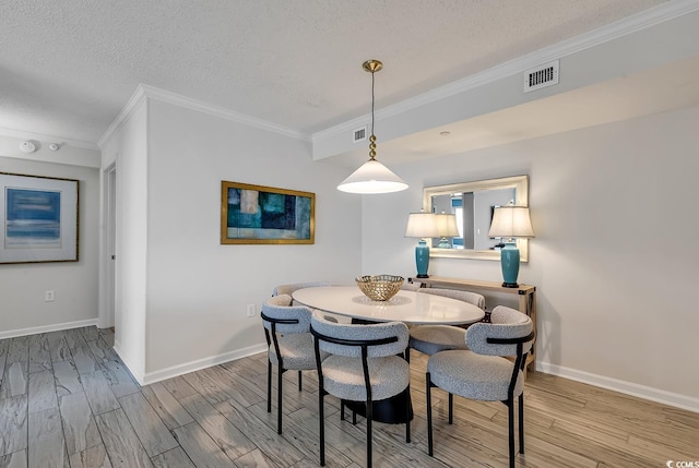 dining space with wood-type flooring, a textured ceiling, and ornamental molding