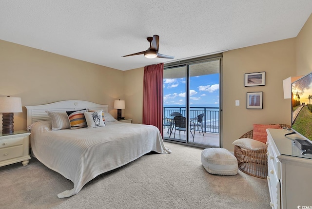 bedroom featuring access to outside, expansive windows, carpet flooring, ceiling fan, and a textured ceiling