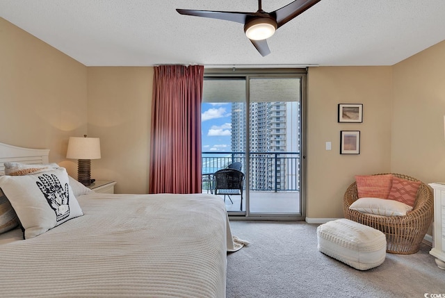 carpeted bedroom featuring ceiling fan, expansive windows, access to exterior, and a textured ceiling